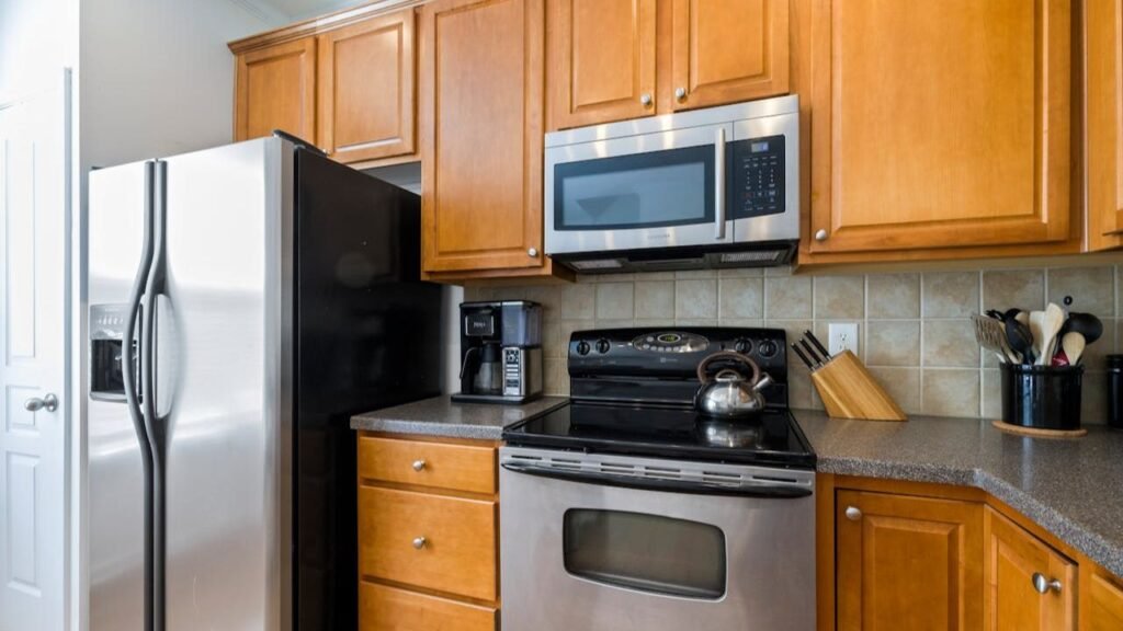 Modern kitchen with stainless steel refrigerator, microwave, oven, and wooden cabinets.